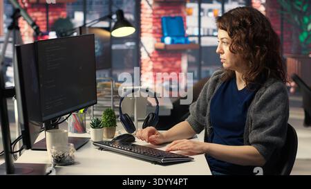 Woman IT developer using pc setup for artificial intelligence cloud computing through self learning algorithms. Agency system engineer works with AI deep neural networks on desktop. Camera B. Stock Photo