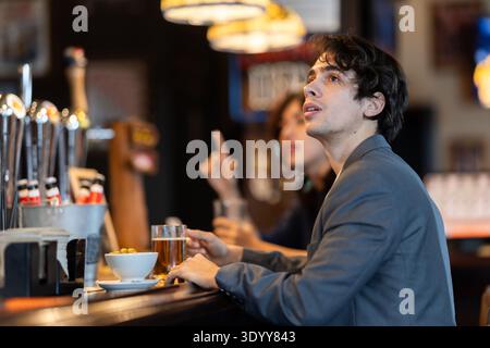 Young man drinks beer and watches match at bar Stock Photo