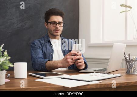 Serious young businessman using mobile in office Stock Photo