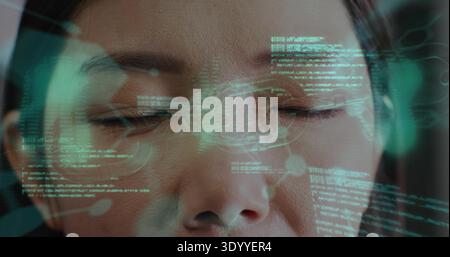 Projecting cyan-green HUD over Chinese woman's face at clinical scan, displaying facial data Stock Photo