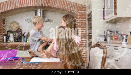 Helping woman in striped top guiding kids doing math at kitchen table with tablet and notebooks Stock Photo