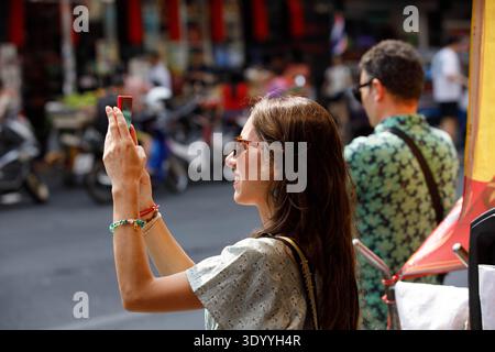 BANGKOK, THAILAND-FEB 15, 2026: Female tourist taking photo, travel lifestyle and digital behavior, side profile, at Yaowarat. Stock Photo