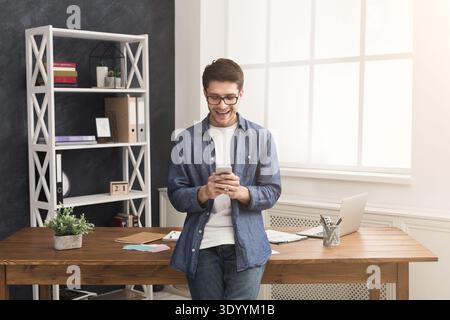 Relaxed young businessman using mobile in office Stock Photo