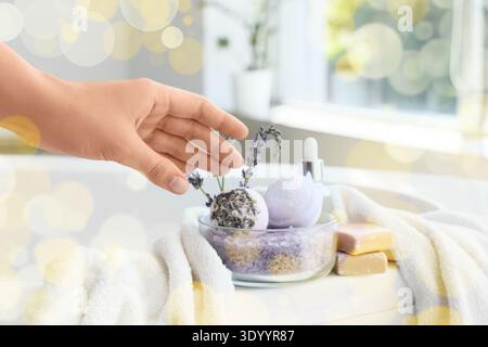 Hand of woman taking lavender bath bombs from bathtub, closeup Stock Photo