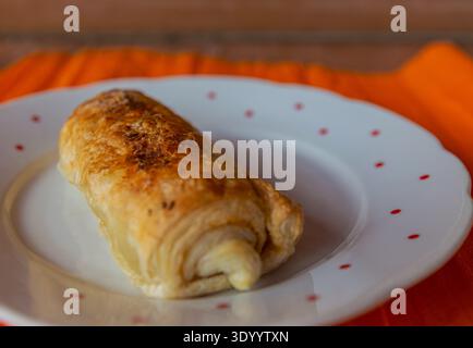 Golden-brown flaky puff pastry roll filled with savory ham and melted cheese. Stock Photo