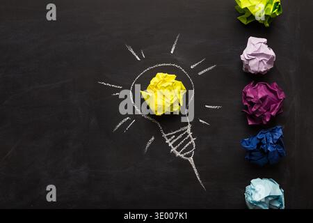 Electric bulb drawn on chalkboard with yellow paper for glowing light Stock Photo