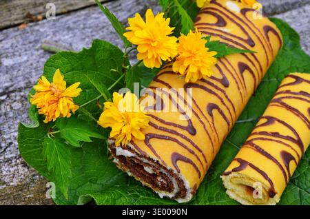 Attractive roll in chocolate and flowers. Stock Photo