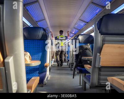 A Deutsch Bahn (German Train Operator) security guard walks along a carriage on an S-Bahn train travelling to Dessau from Halle (Saale) in Germany. Stock Photo