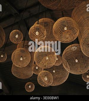 Cluster of woven wicker lampshades hanging closely from the ceiling. Decorative natural fiber lighting design for interior spaces Stock Photo