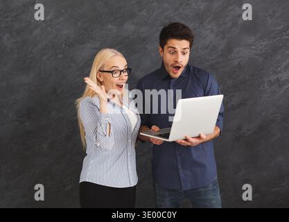 Shocked couple using laptop at studio Stock Photo