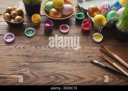 Colorful easter eggs and brushes on wooden table Stock Photo