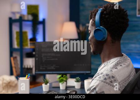 African american programmer with headset programming website code on computer working remote from home. Employee man coding business security server. Concept of software development Stock Photo