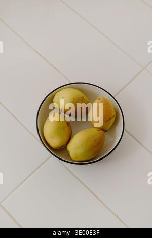 Vertical of Fresh Ripe Pears Arranged in Ceramic Bowl on Tiled Kitchen Surface Stock Photo