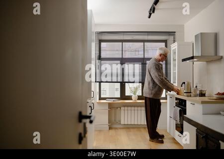 Senior Caucasian Man Preparing Breakfast in Modern Kitchen during Morning Stock Photo