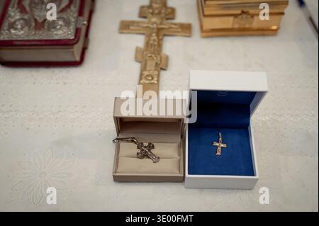 Close up of ornate metal cross necklace in open jewelry case and velvet bound book on white lace cloth conceptual shot of precious gift and historical Stock Photo