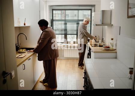 Senior Caucasian Man and Senior Black Woman Preparing Food in Modern Kitchen Stock Photo