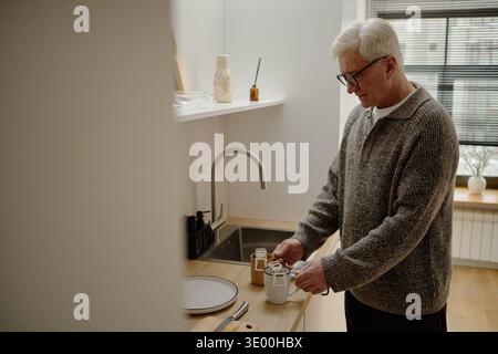 Senior Caucasian Man Preparing Hot Beverage in Modern Kitchen Setting Stock Photo