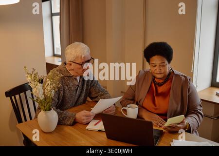Senior Biracial Couple Reviewing Paper Utility Bills Together at Home Stock Photo