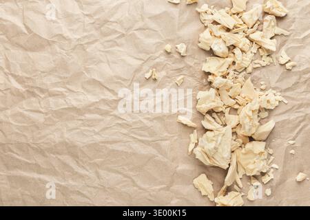 Crushed white chocolate pieces on crumpled craft paper, top view Stock Photo