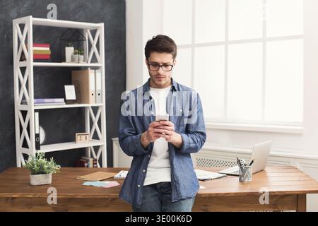 Serious young businessman using mobile in office Stock Photo