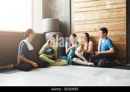 Young men and women having rest after fitness training Stock Photo