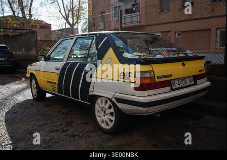 Rear three-quarter view of a vintage Renault 11 GTL hatchback with yellow and black Elf rally livery parked on a city street. Stock Photo