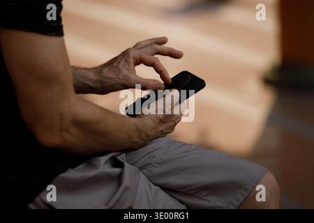Man's hands using smartphone, tourists capturing travel moments with smartphone, daily smartphone activity, modern urban routine, close up Stock Photo