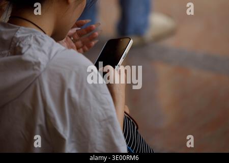 Woman using smartphone, travel lifestyle and digital behavior, casual phone use outdoors, relaxed digital moment, close up. Stock Photo
