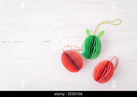 Colorful paper Easter eggs decorations on white wooden background. Top view, flat lay, copy space. Stock Photo