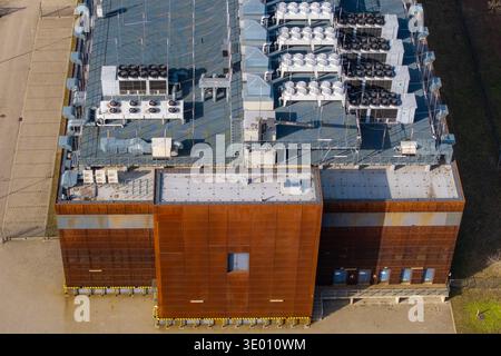 Aerial view of a modern data center building, showing multiple hvac and cooling units on its roof and rusty facade, Warsaw, Masovian Voivodeship, Pola Stock Photo