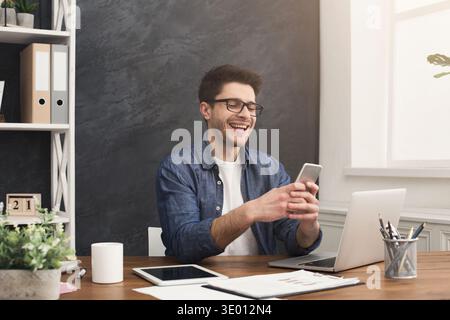 Relaxed young businessman using mobile in office Stock Photo