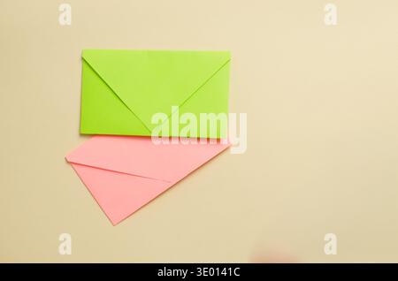 Bright green envelope on top of pink on a light beige background. The contrasting composition of two envelopes symbolizes correspondence, organization Stock Photo