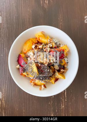 Top view of white plate on wooden table with balanced meal of yogurt, nectarines, walnuts and chia seeds, healthy eating and nutrition Stock Photo