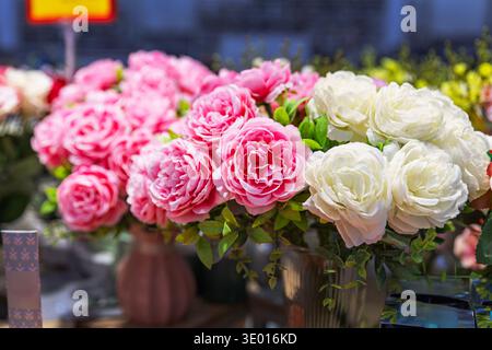 Artificial pink and white peonies in vases on a store counter. Stock Photo