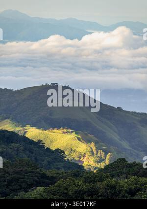 View west from Monteverde resort at sunrise over the hills towards Pacific ocean in vertical format Stock Photo
