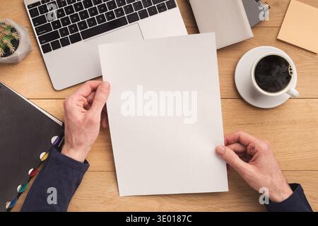 Man holding sheet of paper at workplace Stock Photo