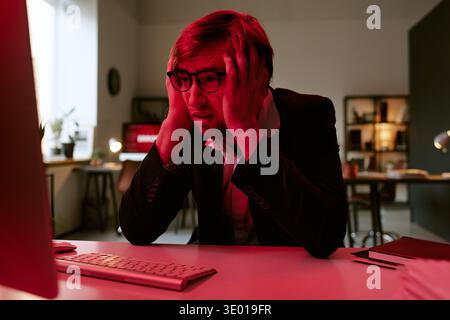 Young Caucasian Man Wearing Glasses Sitting at Desk Feeling Stressed Stock Photo