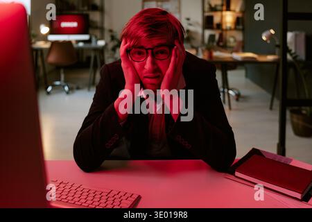Young Caucasian Man Sitting at Desk Feeling Stressed While Working Late Stock Photo