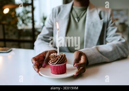 Young Adult Black Woman Holding Cupcake with Lit Candle Celebrating Birthday Stock Photo