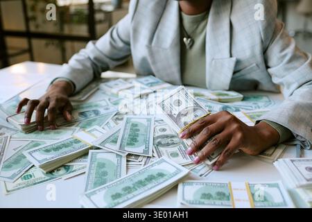 Young Adult Black Woman Counting Cash Money While Sitting at Desk Stock Photo