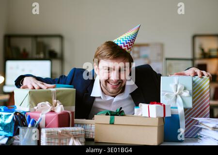 Portrait of Young Caucasian Man Celebrating Birthday Surrounded by Gift Boxes Stock Photo