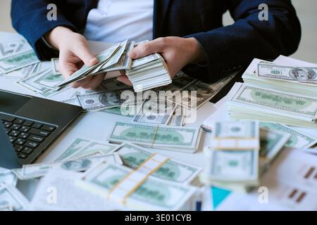 Caucasian Young Adult Man Counting Dollar Banknotes at Office Desk Stock Photo