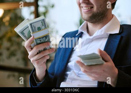 Young Caucasian Man Smiling While Holding Large Stack of Dollar Banknotes Stock Photo