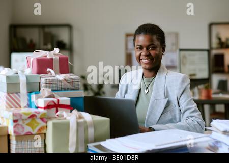 Portrait of Young Adult Black Woman Smiling While Working with Gift Boxes Stock Photo