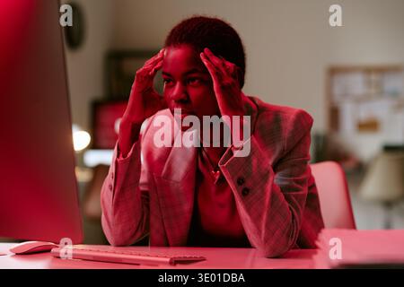 Young Adult Black Woman Concentrating While Working at Computer in Office Stock Photo