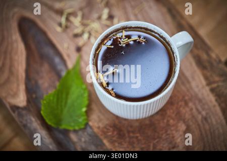 Herbal tea, cup and mint with leaf for vitamin drink, natural medicine or nutrition on wooden table. Top view, beverage or mineral liquid recipe with Stock Photo