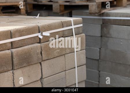 Concrete paving blocks on wooden pallets secured with plastic straps at a construction site. Professional building materials and pavement renovation Stock Photo