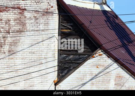 Aged red brick wall with distressed, peeling white paint and weathered texture. Authentic vintage masonry in Menomonie, Wisconsin, USA. Stock Photo