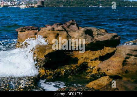 Ocean waves crashing against coastal rocks on Sydney Harbour Stock Photo