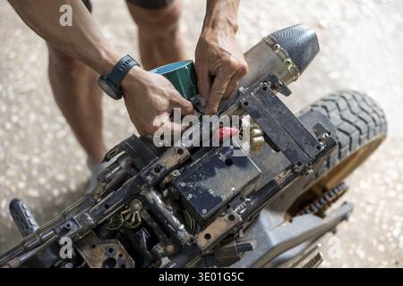 Focused man with skilled hands doing custom motorcycle repair and maintenance. mechanic at work fixing bike in garage, showing concentration and passi Stock Photo
